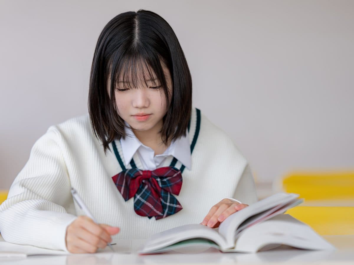 参考書を開いてノートを取る中学生