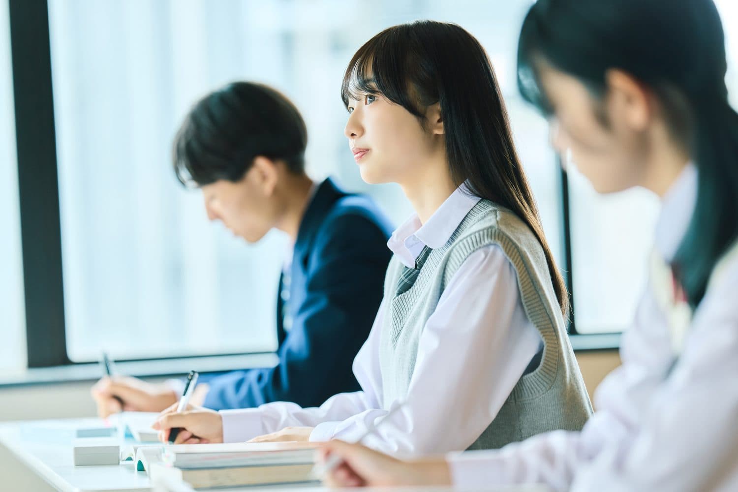 窓辺の教室で机に向かう高校生たち